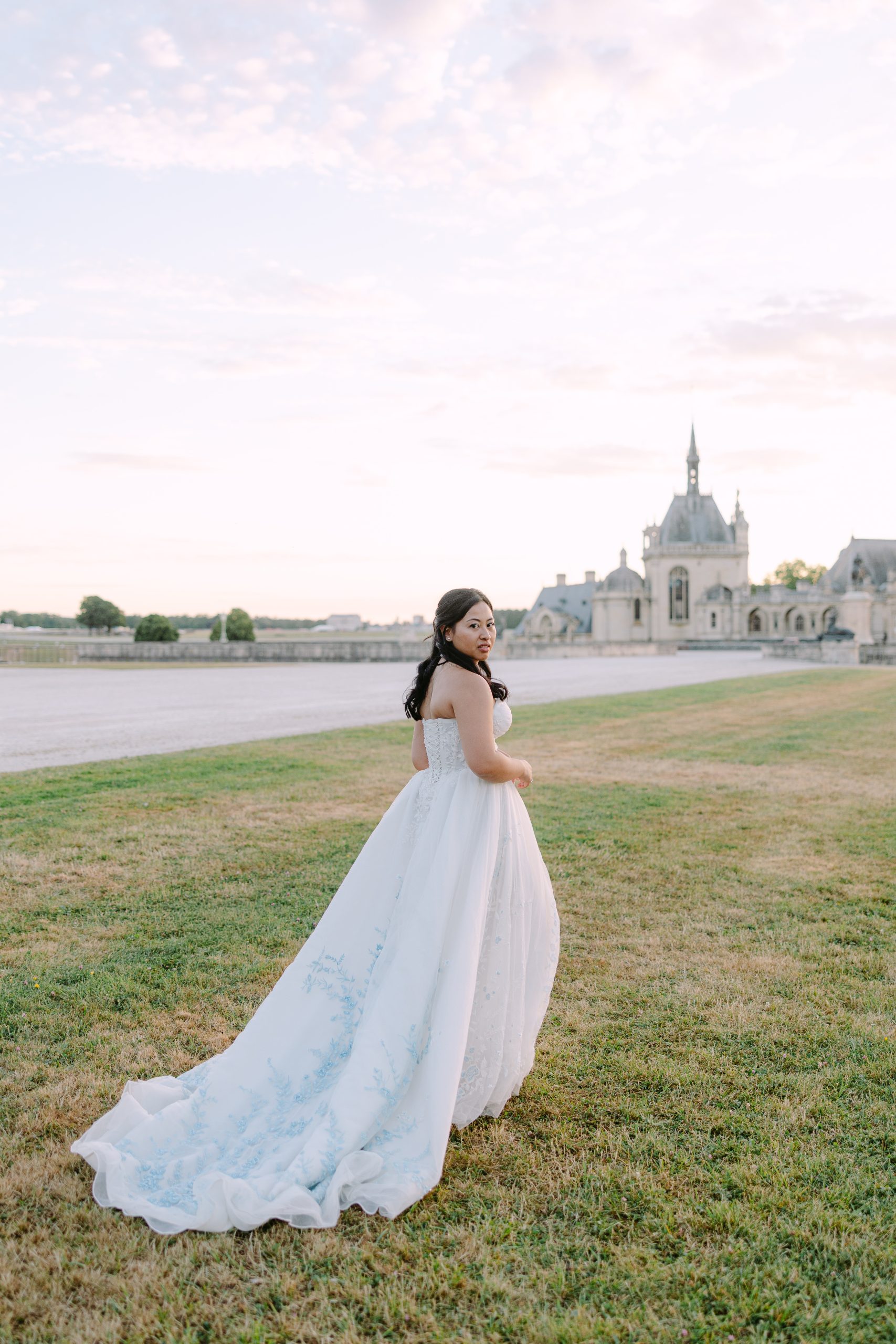 May and Thor sharing a romantic kiss at sunset during their wedding at Château de Chantilly, France.
